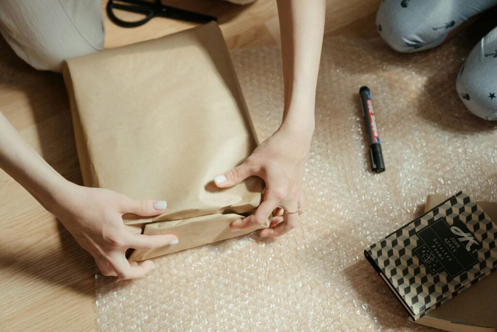 A person wrapping a parcel in kraft paper on top of bubble wrap for protective packaging during shipping