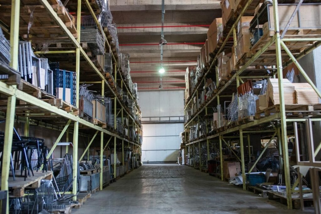Large warehouse aisle with tall pallet racks storing various goods and materials