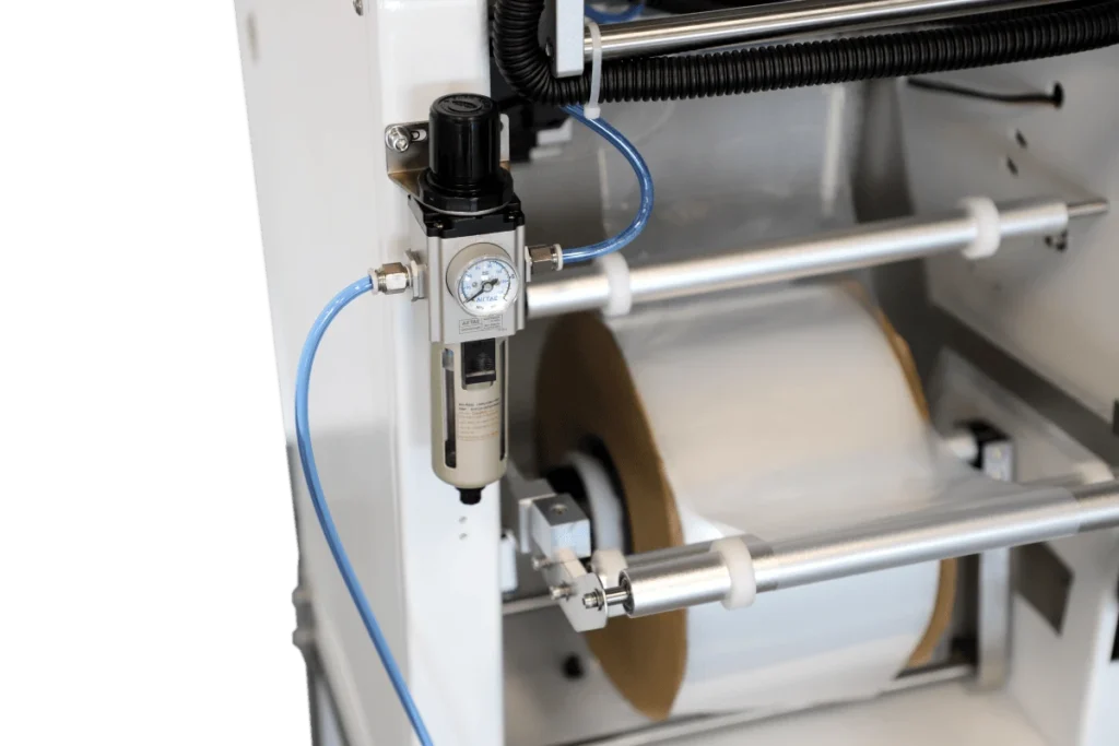 Close-up of pneumatic components and roll holder assembly on an auto bagger