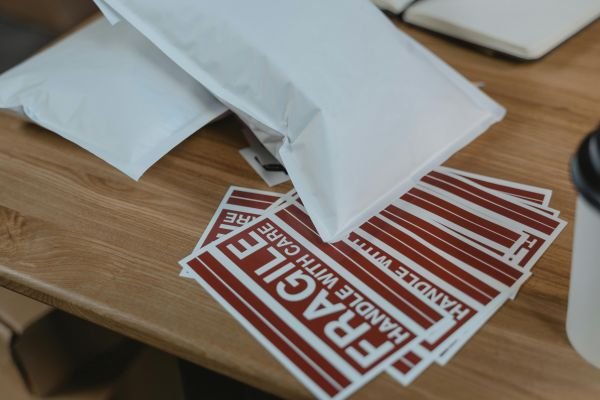 White poly mailer packages stacked on a wooden desk with shipping labels, ready for e-commerce fulfillment. Focus on packaging efficiency and ready-to-ship parcels.