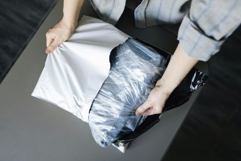 Close-up of hands placing products into different types of pre-opened and stand-up pouches on a workbench in a warehouse, showing correct bag selection and packing process.