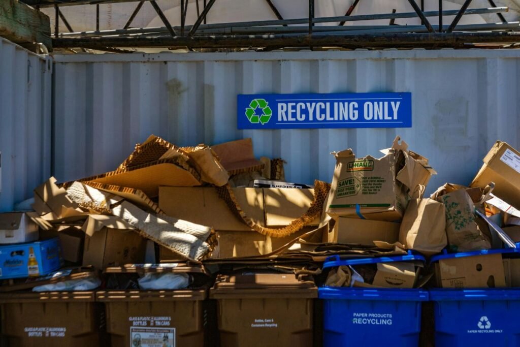 Pile of used cardboard boxes at a recycling station in a warehouse, illustrating cardboard recycling and on-site material reuse for sustainable packaging.