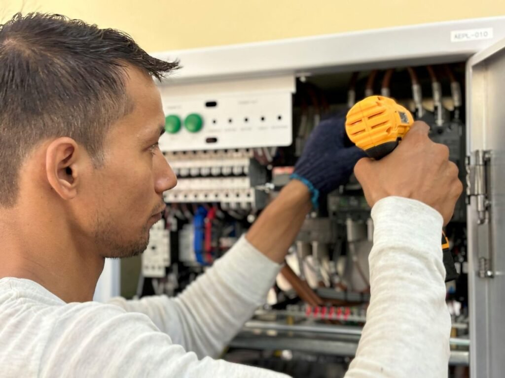Technician using a screwdriver to adjust electrical components in a bagging machine control panel