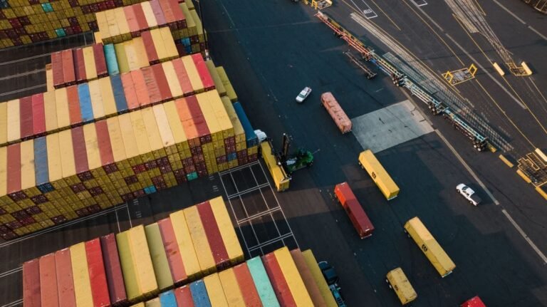 Container yard with stacked shipping containers and logistics traffic for pallet strapping and transport operations
