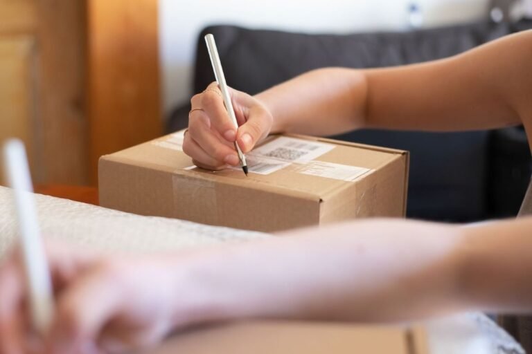 Une personne écrit sur un carton d'expédition scellé lors des vérifications finales d'emballage et d'étiquetage.