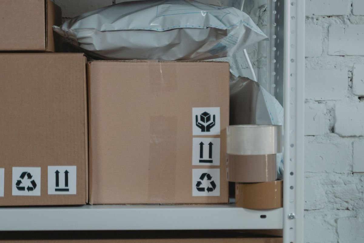 Warehouse shelf with packed cartons, mailing bags, fragile labels, and packing tape