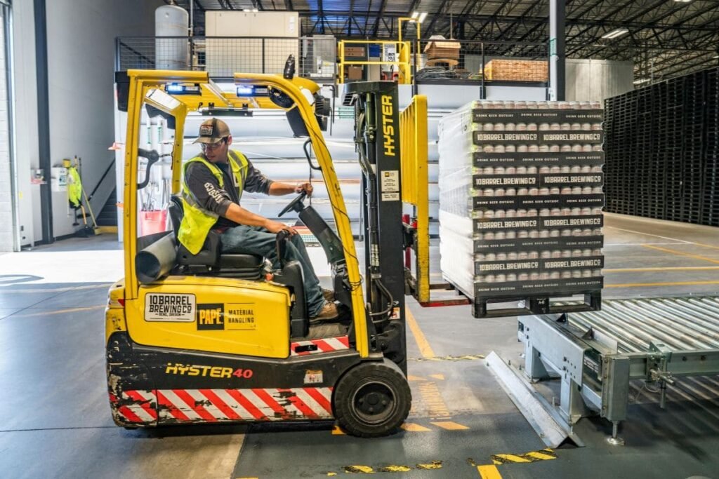Empilhadeira movimentando mercadorias paletizadas dentro de um armazém industrial.