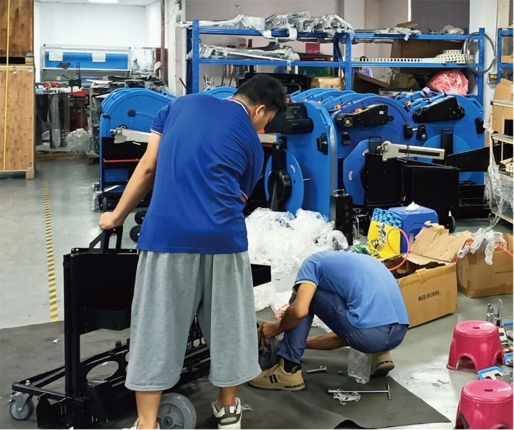 Operários montando uma máquina de cintar paletes na fábrica.