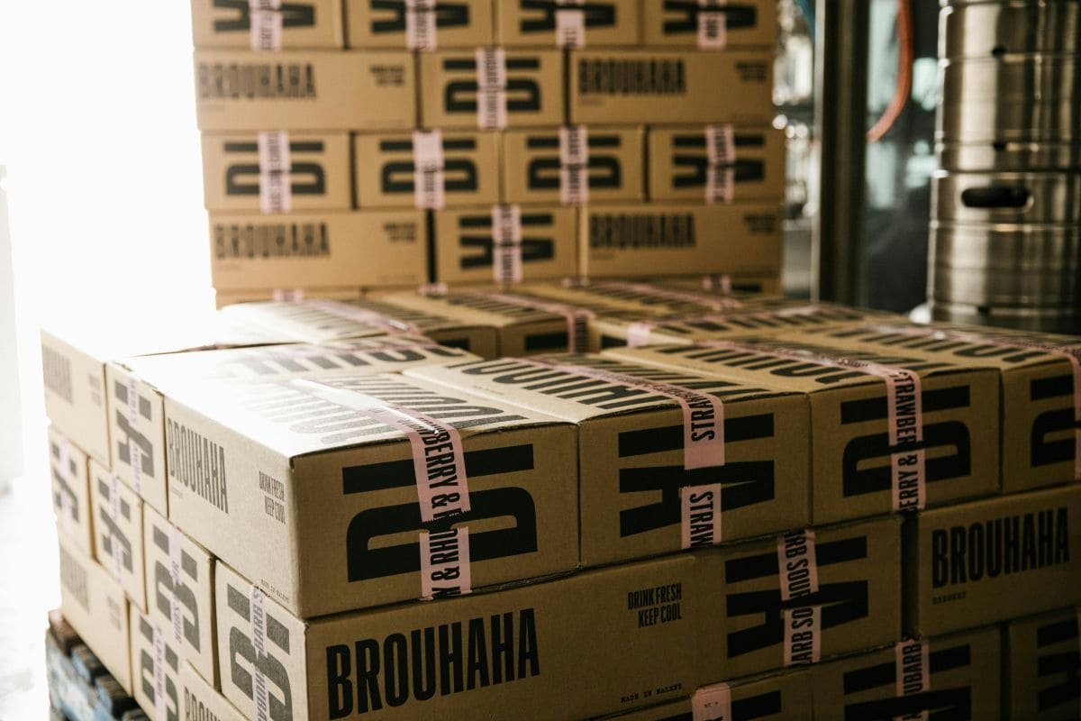 Cajas de cartón apiladas y sujetas con flejes de plástico sobre un palé de almacén.