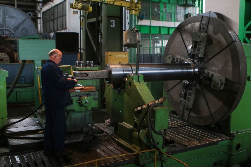Operador verificando uma grande máquina industrial antes do início da produção normal.