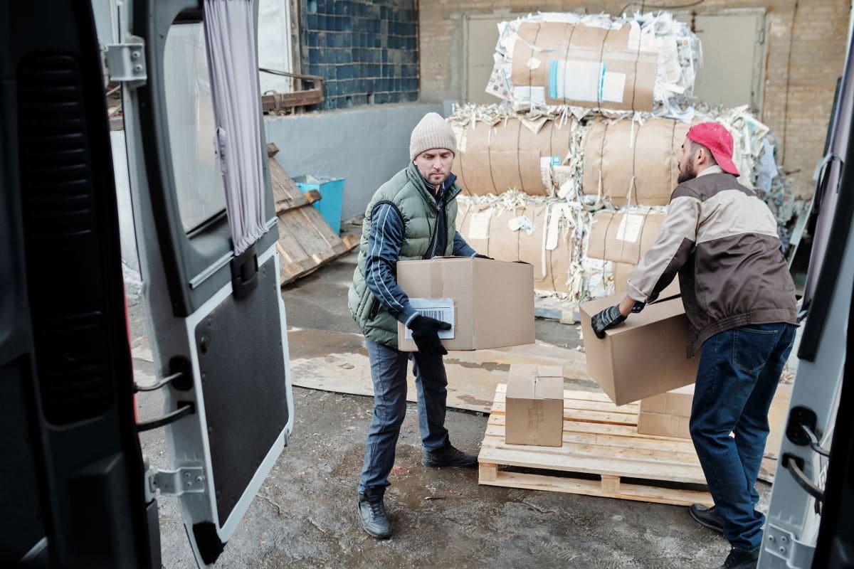 Arbeiter verladen Kartons zum Versand und veranschaulichen so die Anwendungsmöglichkeiten von Schutzschaumverpackungen.