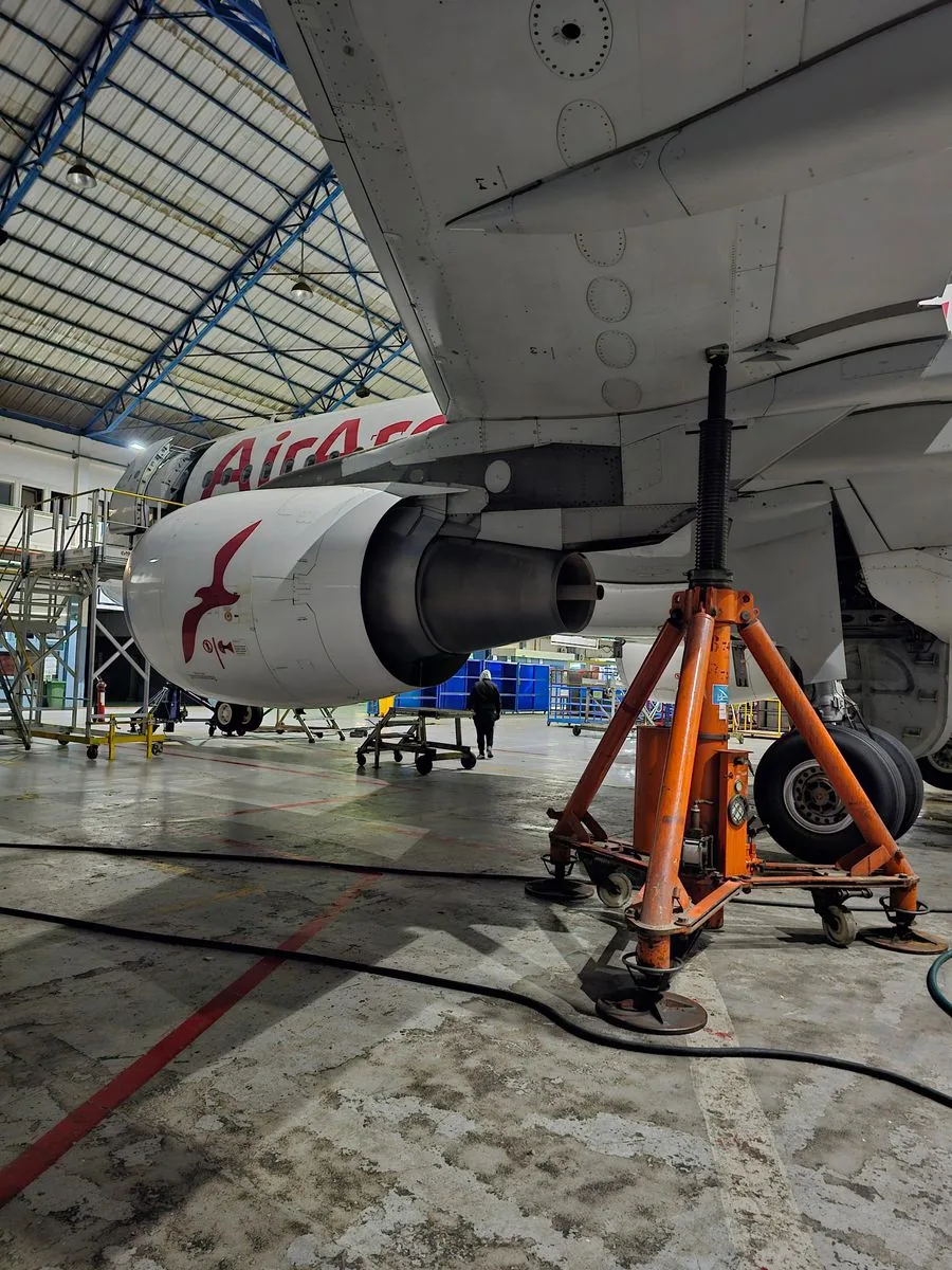 Aircraft undergoing jet engine maintenance inside an industrial hangar