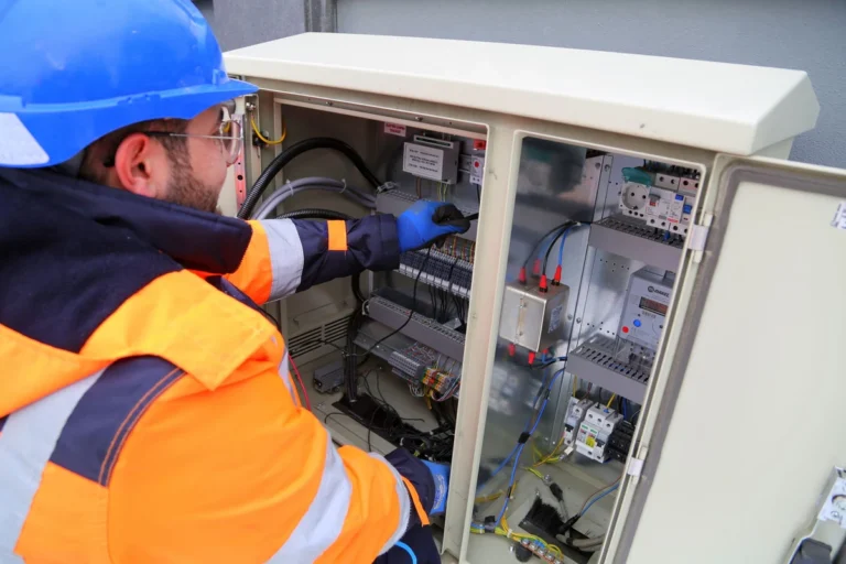 Technicien effectuant la maintenance d'un panneau de commande électrique lors de l'entretien d'une machine à emballer sous film rétractable
