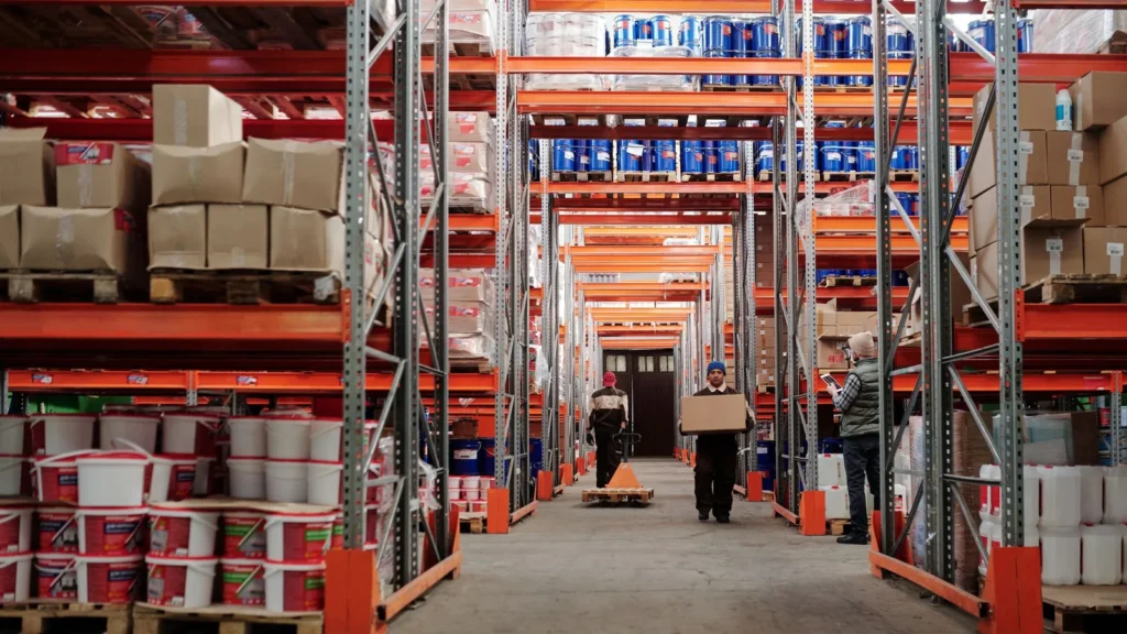 Warehouse workers handling cartons and palletized goods in a storage facility