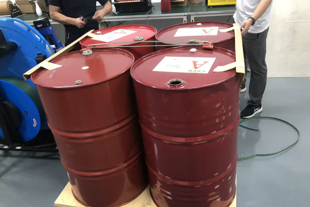 Narrow edge protectors held with tape along the upper edges of four red steel drums.