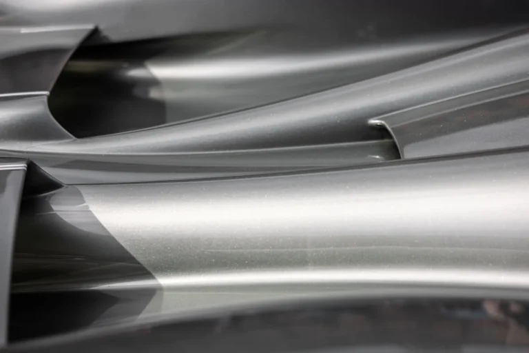 Close-up of curved metallic surfaces with smooth edges and reflected light.