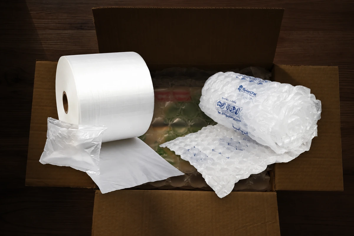 A pillow film roll and a rolled bubble sheet displayed against a darkened open-carton background.
