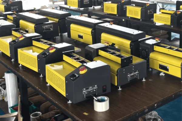 Row of yellow and black automatic bagging machines on assembly tables in a factory