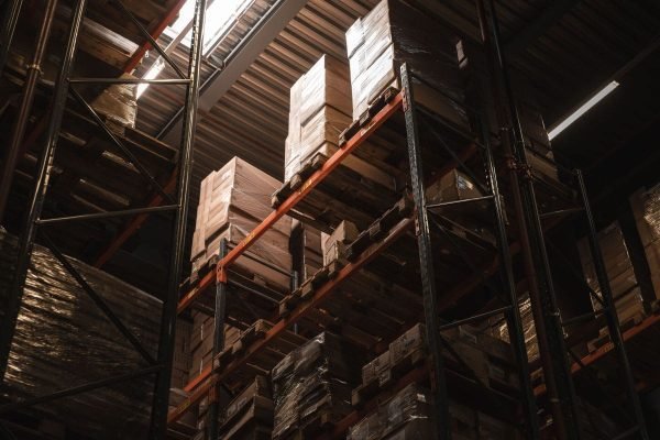 Rayonnages d'entrepôt avec cartons palettisés stockés en vue de leur cerclage industriel et de leur préparation à l'expédition